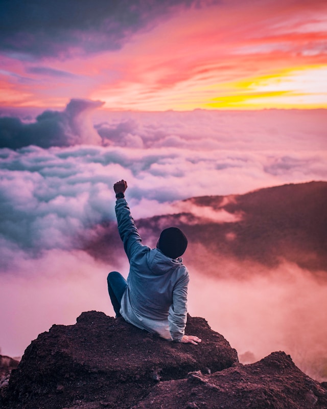 Meditador sentado en la cima de una montaña al atardecer