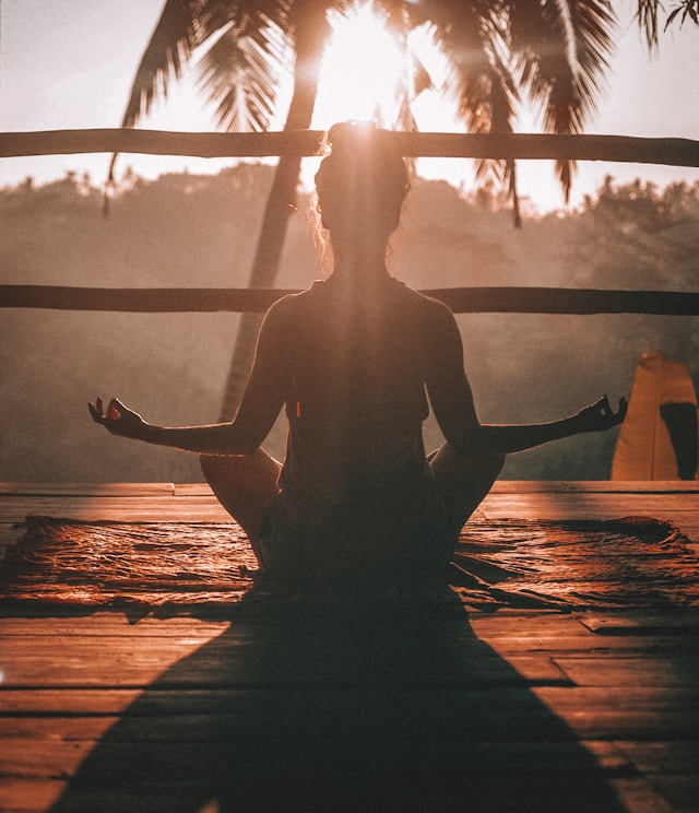 Mujer meditando al atardecer en conexión con el universo