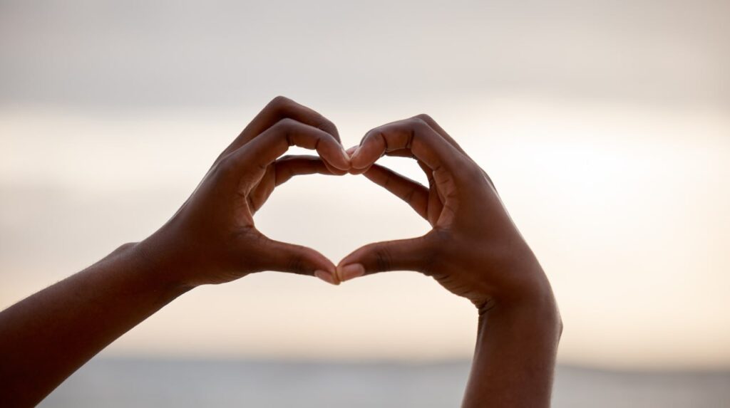 Manos formando un corazón hacia el cielo como símbolo de amor universal y conexión espiritual